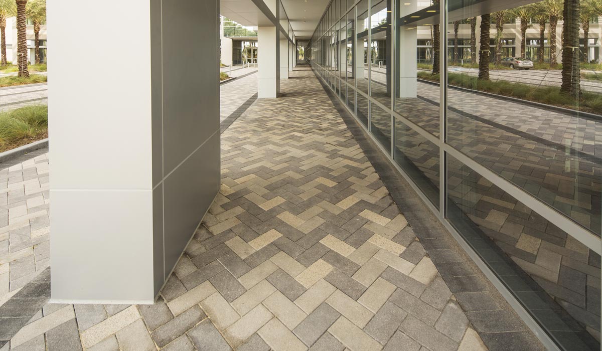 This building has a herringbone pattern walkway. The pavers are gray and beige.