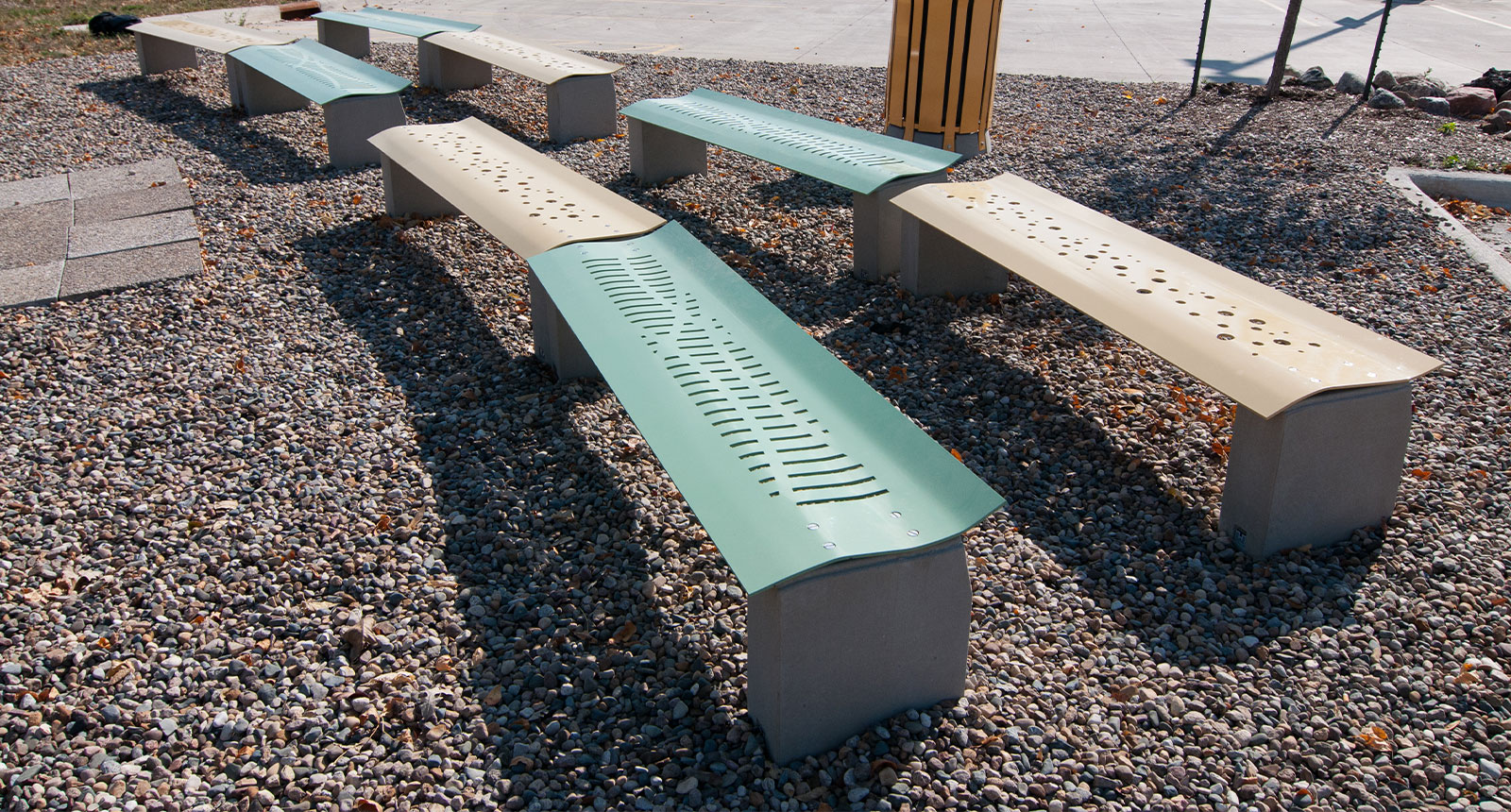 A gravel area with alternating yellow and green benches with circular and linear engravings.