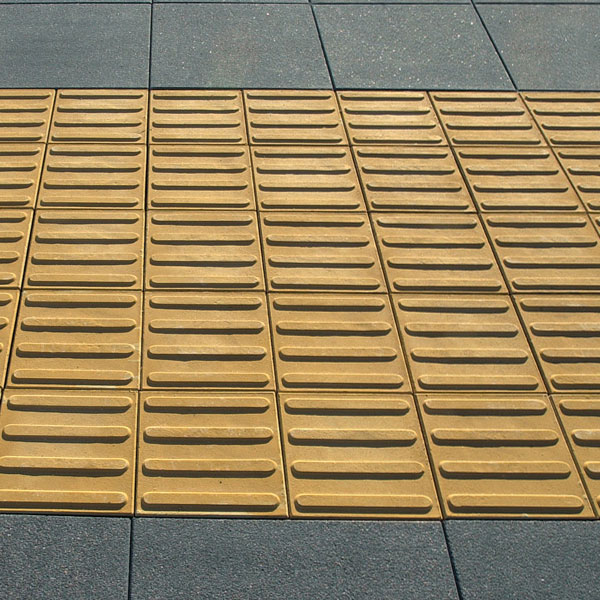 A close-up image of directional and tactile pavers in a yellow color.