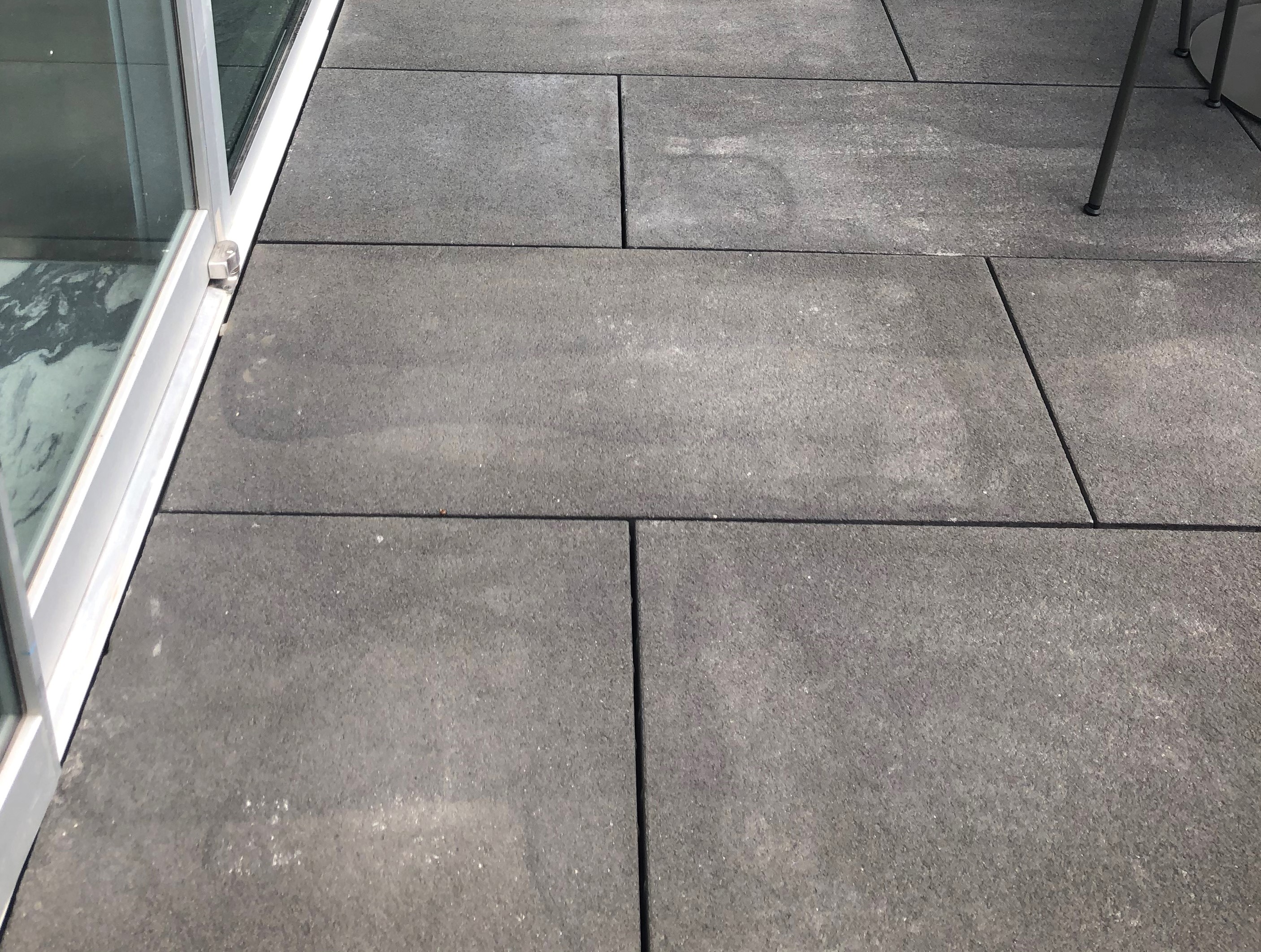 Dark gray, rectangular concrete pavers with lighter areas of efflorescence.