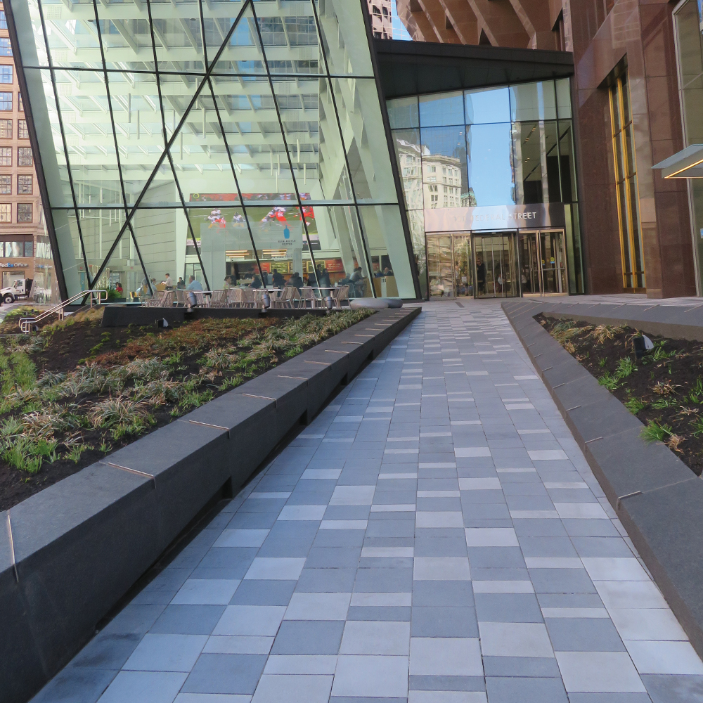 These light gray and white square pavers lead up to a front door of a large building.