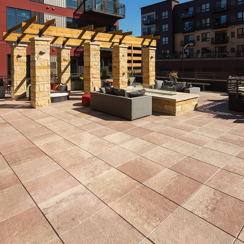 This rooftop lounge area has two sofas and a large fire pit.