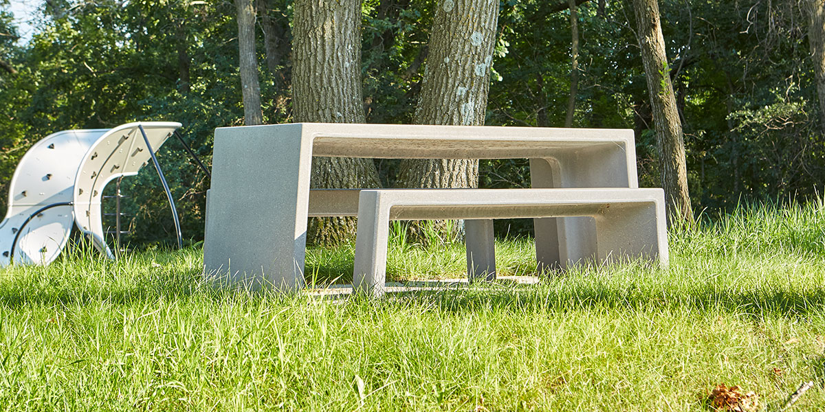 A grassy rest area with rectangular concrete benches.