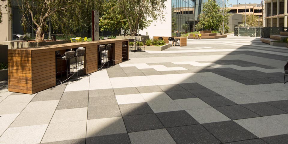This outdoor area has white, tan and gray square pavers. There is an outdoor eating area.